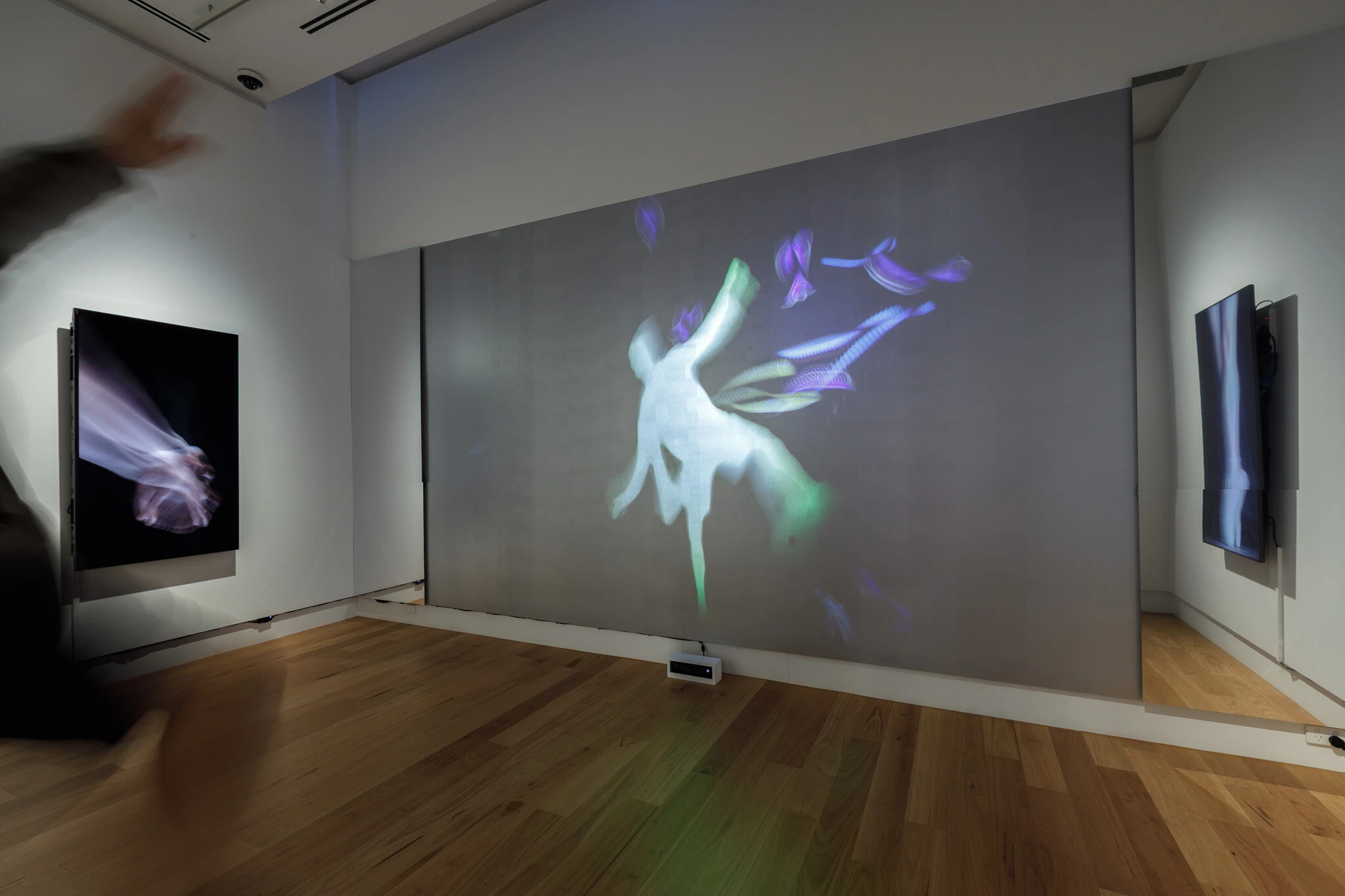 Installation view of Lift by Anne Scott Wilson at Wyndham Art Gallery, showing large-scale projection with dancer silhouette and motion-capture interaction, flanked by video screens