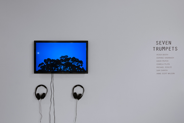 A wall-mounted screen showing a deep blue night sky over dark treetops, with two pairs of headphones below