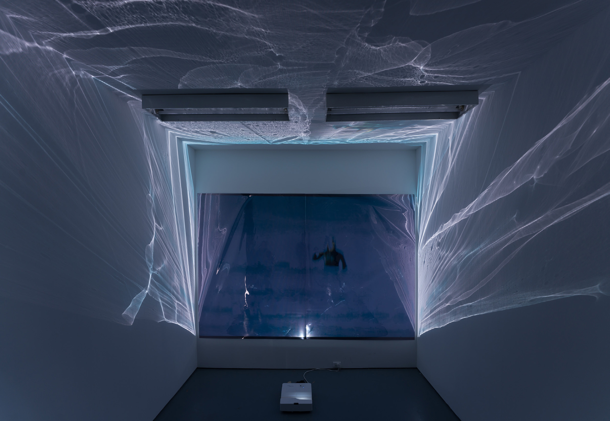 Viewer experiencing VR work in Spin Into Being, with projected water and light enveloping the gallery space